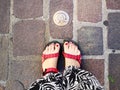 Foot wearing sandals near a turistic brass plaque