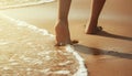 The foot of woman, walking on sand beach, in sunset light with a soft wave, at summer beach, overlooking footprint on the beach,