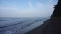 footage of sea waves on the beach during the day but the weather is smoky