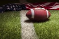 Football and American flag on grass field with stripe in dramatic light Royalty Free Stock Photo