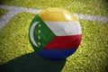 Football ball with the national flag of comoros lies on the green field