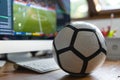 Football coach analyzes football stats on a computer with a football resting on the desk Royalty Free Stock Photo