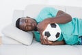 Football fan hugging ball on couch Royalty Free Stock Photo