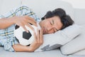 Football fan hugging ball on couch Royalty Free Stock Photo