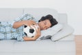Football fan hugging ball on couch Royalty Free Stock Photo