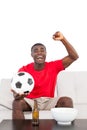 Football fan in red jersey sitting on couch cheering