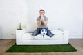 Football fan watching television soccer match suffering stress praying god Royalty Free Stock Photo