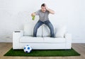 Football fan watching tv match on sofa with grass pitch carpet in stress Royalty Free Stock Photo