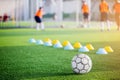 Football on green artificial turf with blurry of maker cones and