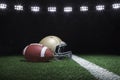 Football and helmet on grass field below stadium lights at night Royalty Free Stock Photo