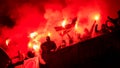 Football hooligans with mask holding torches in fire