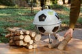 Hand puts piece of wood in round barbecue