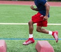 Football player running over red barriers during summer practice