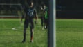 Soccer player runs, hits the ball and misses past the net, blurred for background
