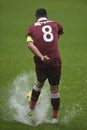 Football player shooting ball on flooded field