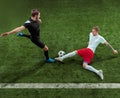 Football players tackling ball over green grass background Royalty Free Stock Photo