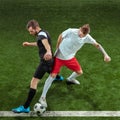 Football players tackling ball over green grass background Royalty Free Stock Photo