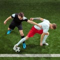 Football players tackling ball over green grass background Royalty Free Stock Photo