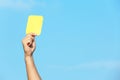 Football referee showing yellow card against blue sky Royalty Free Stock Photo