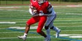 Football running back fighting off a tackler