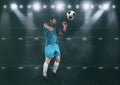 Football scene at night match with player jumping to hit the ball with head Royalty Free Stock Photo