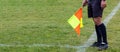 Football soccer arbiter assistant with flag at hands. Blurred green field background