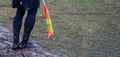 Football soccer arbiter assistant with flag at hands. Blurred green field background