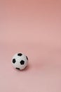 Football or Soccer ball, classic black and white isolated on light pastel coral background. Vertical with copy space. Small soft Royalty Free Stock Photo