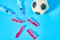Football, soccer ball near syringe and ampoule on blue background. Concept of doping in professional sport Royalty Free Stock Photo