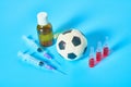 Football, soccer ball near syringe and ampoule, bottle on blue background. Concept of doping in sport Royalty Free Stock Photo