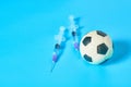 Football, soccer ball near syringe on blue background. Concept of doping in professional sport Royalty Free Stock Photo