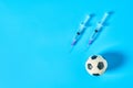 Football, soccer ball near syringe on blue background. Concept of doping in professional sport Royalty Free Stock Photo