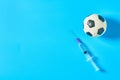 Football, soccer ball near syringe on blue background. Concept of doping in professional sport Royalty Free Stock Photo