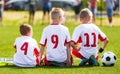 Football soccer game for children. Kids substitute players sitting on a bench.