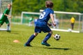 Young Soccer Players Running After the Ball. Kids in Soccer Red and Blue Uniforms. Soccer Stadium in the Background Royalty Free Stock Photo