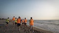 Football sport team is engaged in jogging training at sea at sunrise