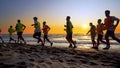 Football sport team is engaged in jogging training at sea at sunset