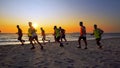 Football sport team is engaged in jogging training at sea at sunset