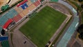 Football stadium in the city park. A green field and stands are visible, painted in different colors. Close-up shot. Aerial Royalty Free Stock Photo