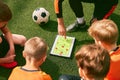 Football training. Soccer coach explaining game rules and strategy using tablet, map. Sports junior team sitting on Royalty Free Stock Photo