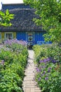 Footpath through beautiful flowerbeds to an old wooden house