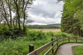Footpath through Hafren Forest, Wales, with a stormy summer sky and view over lush countryside