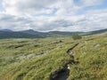 Footpath in northern artic landscape, tundra in Swedish Lapland with green hills,mountains and lake at Padjelantaleden