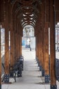 A footpath underneath a brown wooden pergola at a bus station with black metal benches and trash cans on a cloudy day in Nashville