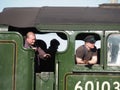 The footplate crew of steam locomotive Flying Scotsman number 60103 wave from the engine cab in close up
