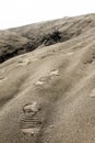 Footprint on blown sand heading toward white sky.