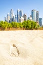 Footprint in the sand and Dubai skyline, UAE