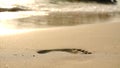 Footprints on beach sand and surging wave