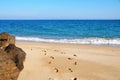 Footprints on an empty sandy beach, large stones on the shore, sea horizon and clear sky Royalty Free Stock Photo