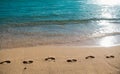 Footprints at golden sand, footsteps. Beach background. Calm beautiful ocean wave on sandy beach. Sea view from tropical Royalty Free Stock Photo